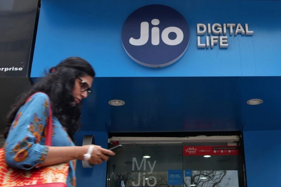 A woman checks her mobile phone as she walks past a mobile store of Reliance Industries' Jio telecoms unit, in Mumbai, India, July 11, 2017. REUTERS/Shailesh Andrade