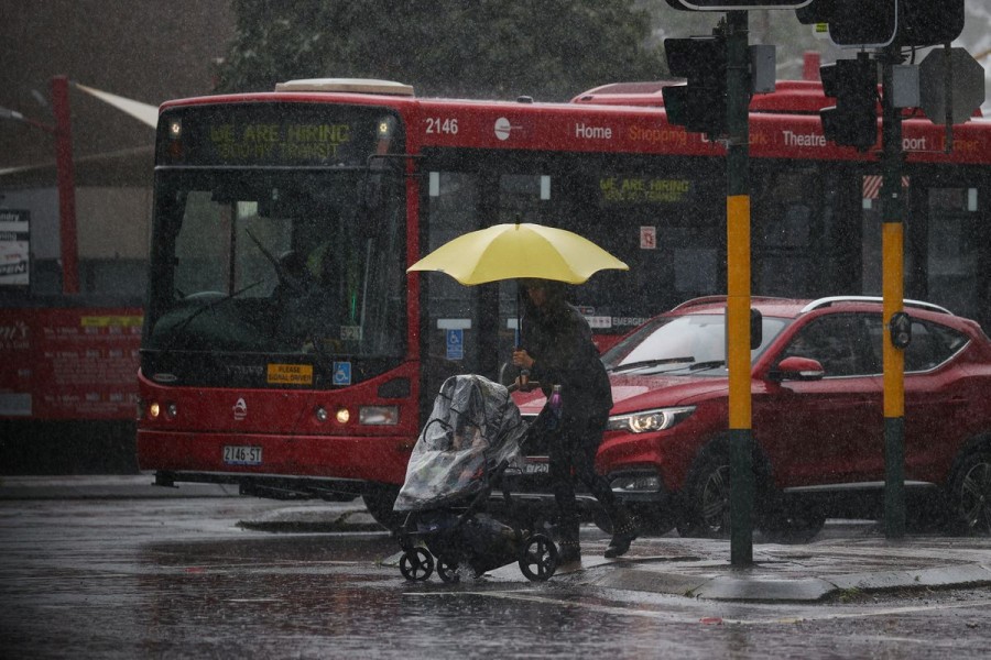 A pedestrian pushing a baby pram crosses a flooding intersection as heavy rains affect Sydney, Australia, October 6, 2022. REUTERS/Loren Elliott/File Photo