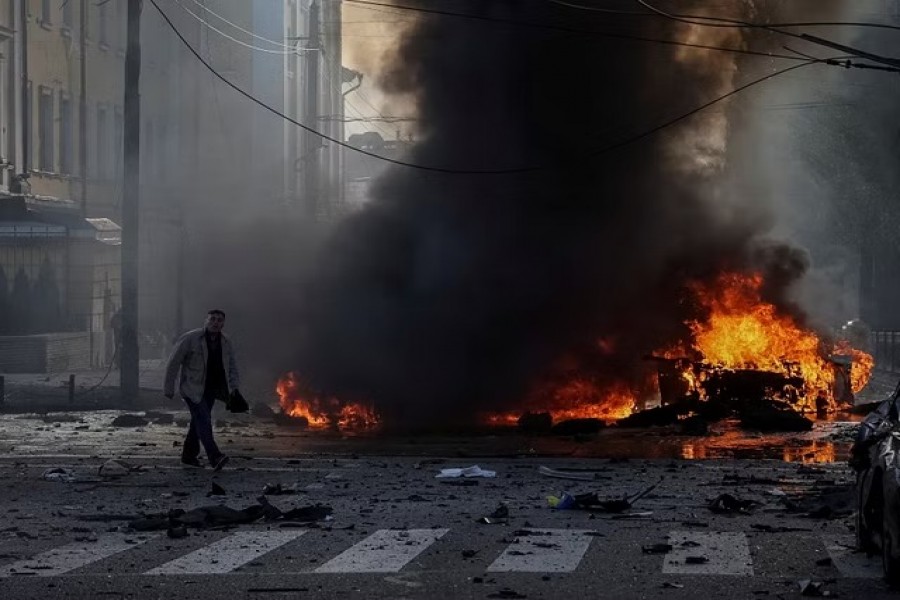 A driver walks near his burned car after Russian military strike, as Russia's invasion of Ukraine continues, in central Kyiv, Ukraine, Oct 10, 2022.REUTERS