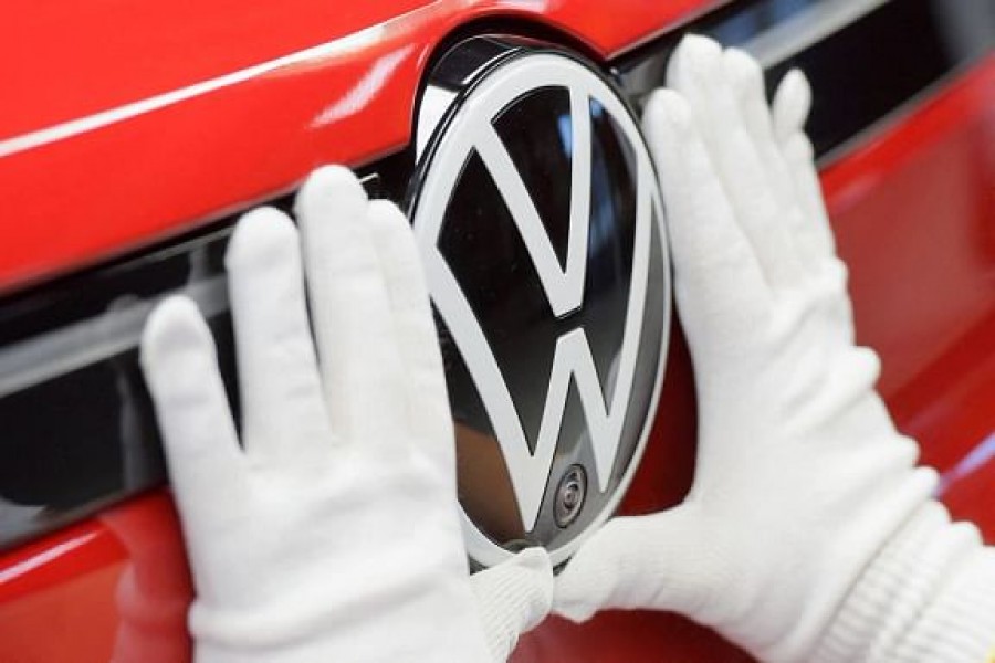 A technician attaches a Volkswagen logo to a car, at the production line for electric car models of the Volkswagen Group, in Zwickau, Germany, April 26, 2022. |REUTERS