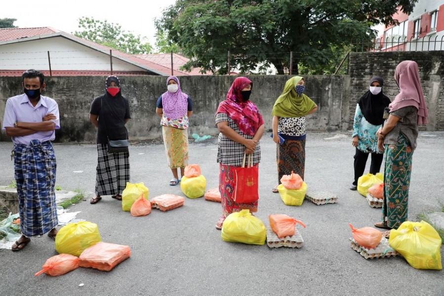 Rohingya refugees wearing protective masks keep a social distance while waiting to receive goods from volunteers, during the movement control order due to the outbreak of the coronavirus disease (COVID-19), in Kuala Lumpur, Malaysia April 7, 2020. REUTERS/Lim Huey Teng/File Photo/File Photo