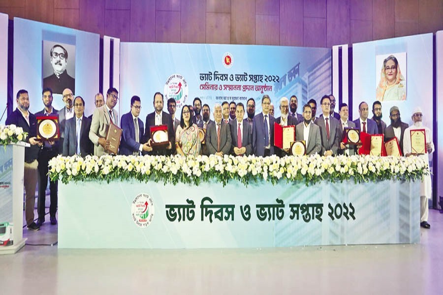 Finance Minister AHM Mustafa Kamal, FBCCI President Md Jashim Uddin and NBR Chairman Abu Hena Md Rahmatul Muneem pose with others at the top tax payers certificate distribution ceremony on the occasion of National VAT Day at a city hotel on Saturday — FE Photo