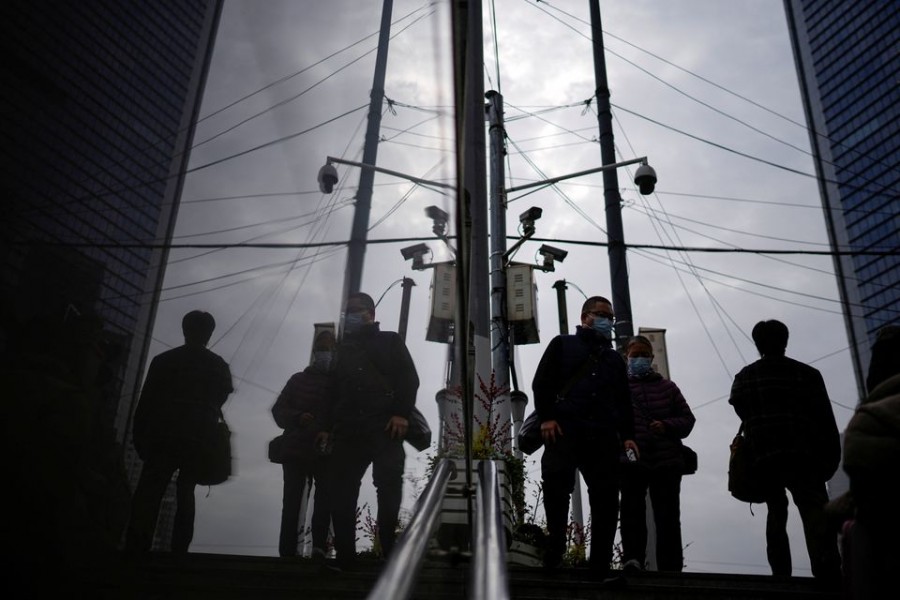 People wearing face masks walk under surveillance cameras on a street, as coronavirus disease (COVID-19) outbreaks continue in Shanghai, China, December 12, 2022. REUTERS/Aly Song