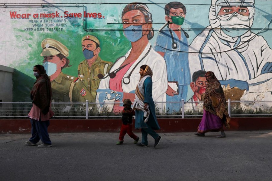 Women walk past a graffiti amidst the spread of the coronavirus disease (Covid-19) in New Delhi, India on February 7, 2022 — Reuters/Files