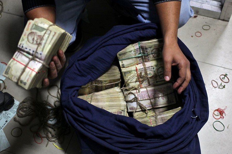 A bank employee takes out a bundle of old 500 Indian rupee banknotes from a sack to count them inside a bank in Jammu on November 25, 2016 — Reuters/Files