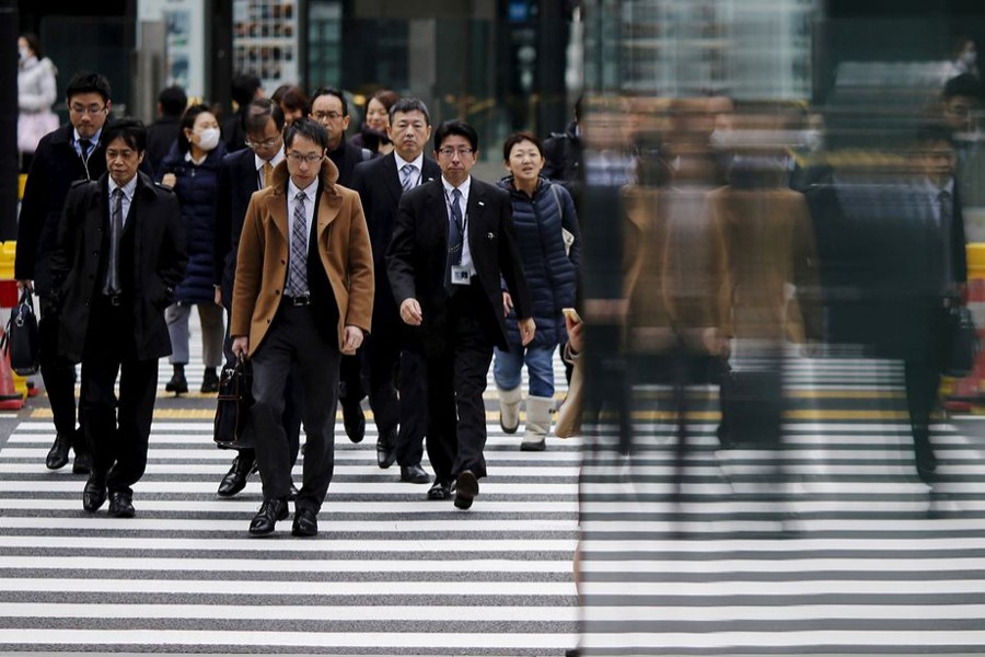 People are reflected on a wall as they cross a road at Tokyo's business district, Japan on February 22, 2016 — Reuters/Files