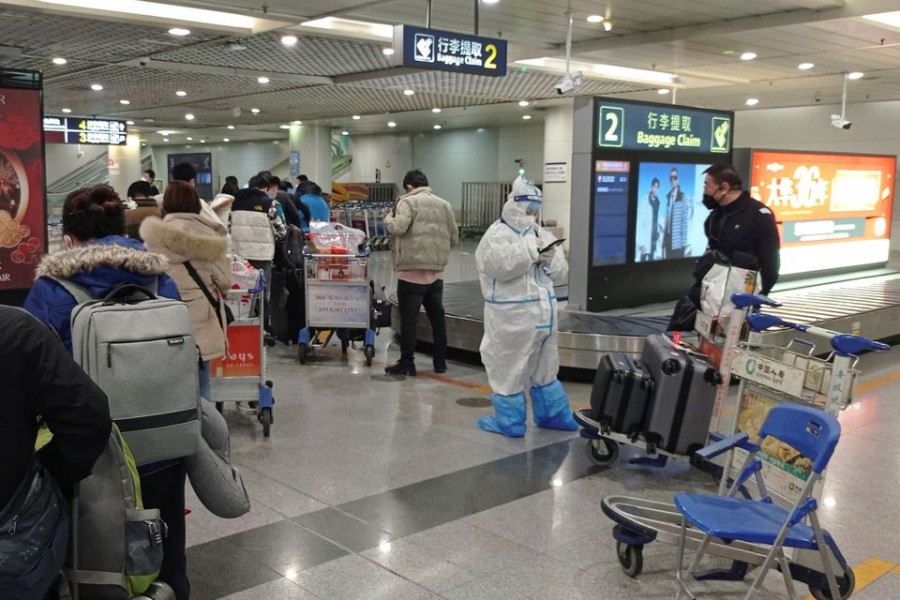 Passengers arriving on international flights wait in line next to a staff member wearing personal protective equipment (PPE) at the airport in Chengdu, China January 6, 2023. REUTERS/Staff