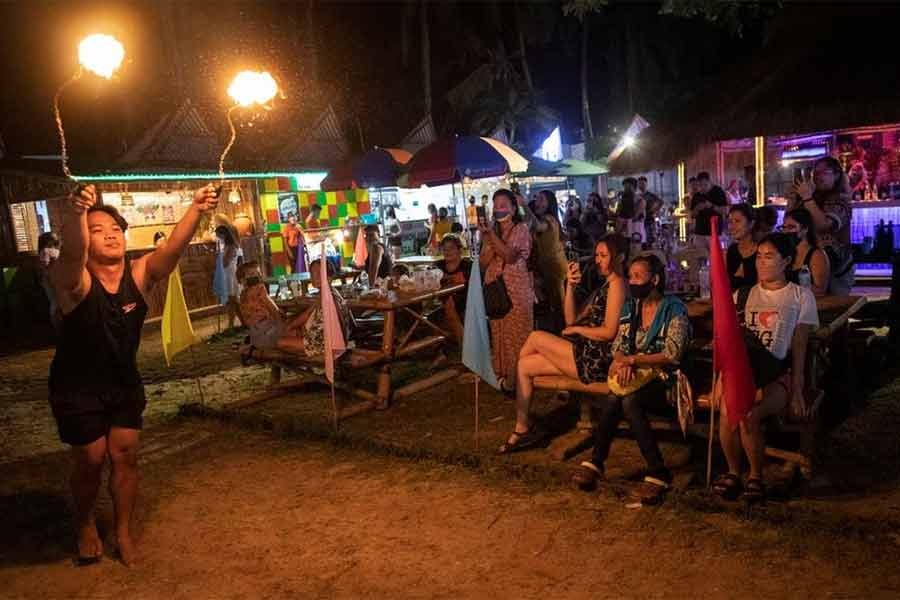 A fire dancer performing for tourists, who are wearing masks for protection against the coronavirus disease (COVID-19), on Boracay Island in Philippines on December 1 in 2021 -Reuters file photo