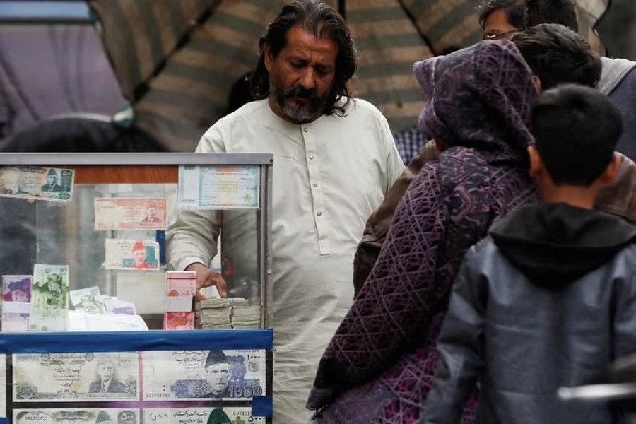 FILE PHOTO: A currency broker stands near his booth, which is decorated with pictures of currency notes, while dealing with customers, along a road in Karachi, Pakistan, Jan 27, 2023. REUTERS