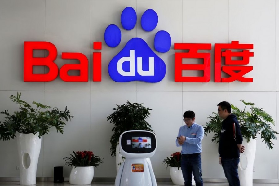 Men interact with a Baidu AI robot near the company logo at its headquarters in Beijing, China April 23, 2021. REUTERS/Florence Lo