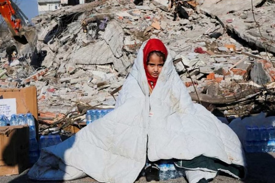 A girl sits near the site of a collapsed building following an earthquake in Kahramanmaras, Turkey Feb 8, 2023. REUTERS