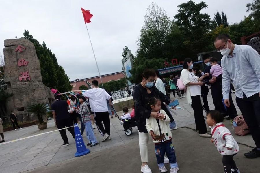 Tourists stand near a Chinese national flag at a tourist site during the National Day holiday, in the outskirts of Beijing, China on October 2, 2022 — Reuters/Files